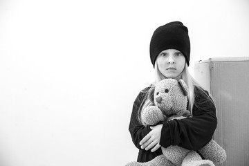 Homeless little girl with teddy bear indoors