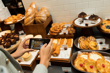 Many Good Looking design and colorful Bakery Cake on wooden tray show, present variety of Price and taste design for special occasion, take photo shoot by mobile phone of skinny asian woman hand