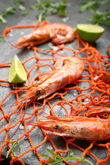 Tasty shrimps with mesh on slate plate, closeup