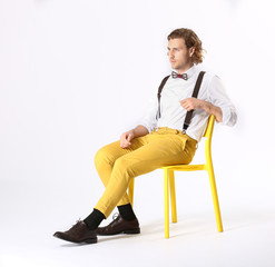 Stylish young man sitting on chair against white background