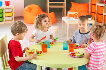 Cute little children eating tasty lunch in kindergarten