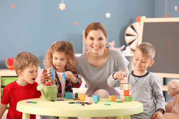 Nursery teacher with cute little children in kindergarten