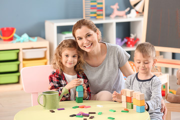 Nursery teacher with cute little children in kindergarten