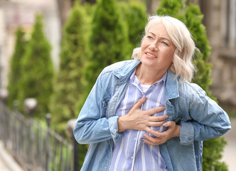 Mature woman suffering from heart attack outdoors