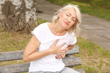 Obraz premium Mature woman suffering from heart attack outdoors