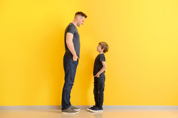Portrait of father and son near color wall - obrazy, fototapety, plakaty