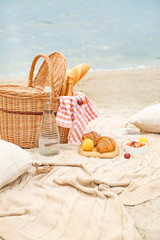 Wicker basket with tasty food and drink for romantic picnic near river