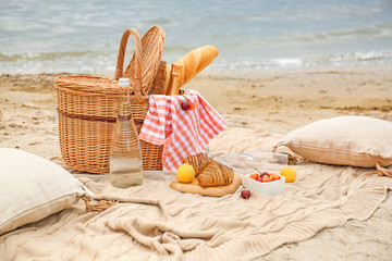 Wicker basket with tasty food and drink for romantic picnic near river
