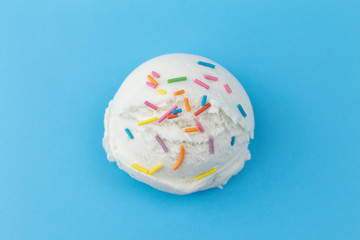 Ice cream close-up. White Ice cream decorated with colorful sprinkles on blue background. Sweet Vanilla flavor dessert.