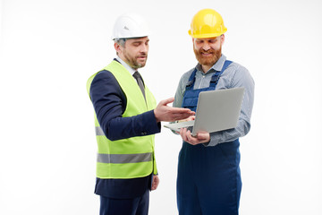 Engineer and foreman are discussing a new project looking at a laptop