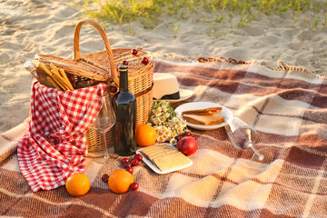 Wicker basket with tasty food and drink for romantic picnic on beach