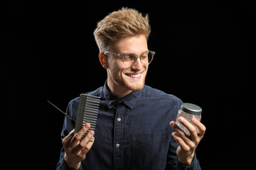 Young male hairdresser on dark background