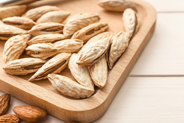 Board with almonds on wooden background, closeup
