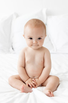 Smiling baby sitting on white bed