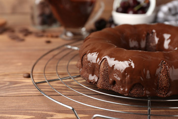 Cooling rack with tasty chocolate cake on wooden table