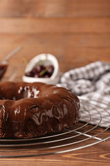 Cooling rack with tasty chocolate cake on wooden table
