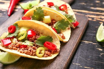 Board with tasty fresh tacos on wooden table, closeup