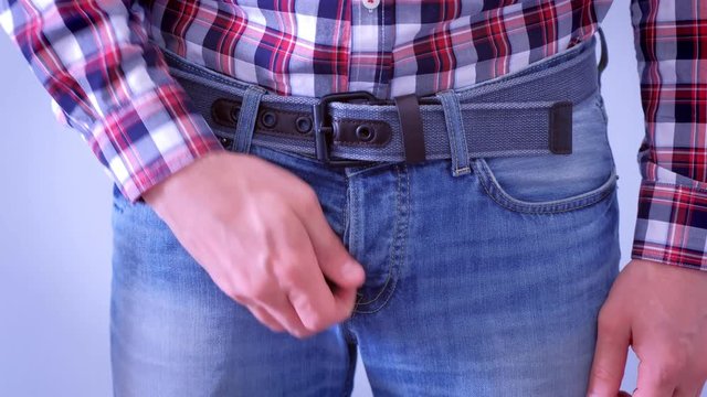 Man is intensively scratching his dick and crotch in jeans, hand closeup. Concept of sexually transmitted diseases.