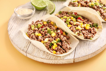 Board with tasty fresh tacos on color background, closeup