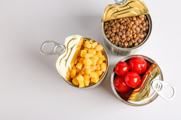Tin cans with different food on light background