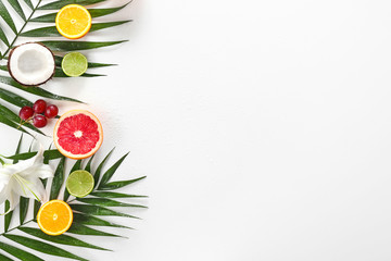 Different fruits and palm leaf on white background