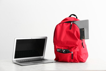 School backpack and laptop on white background