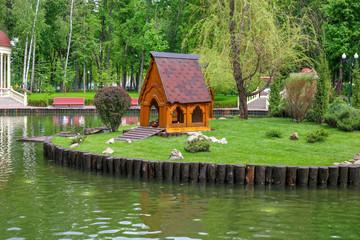 Fototapeta na wymiar Duck house on the lake. Lake with arbor in city park. People have a rest in Park. Landscape design in city park.