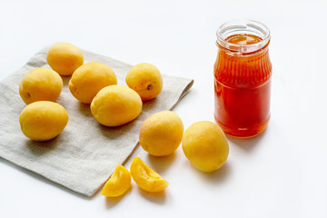 Apricot jam in a jar and fresh fruits on a white background