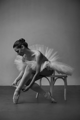 ballet dancer on a chair and tying her ballet slippers, black white © pavlobaliukh