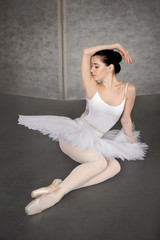 Fototapeta premium Young slim ballerina tired sitting on floor in studio, Concept of ballet art.