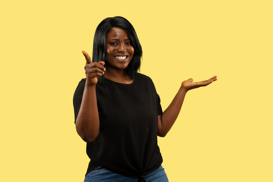 Young african-american woman isolated on yellow studio background, facial expression. Beautiful female half-length portrait. Concept of human emotions, facial expression. Choosing and inviting.