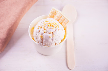 Vanilla ice cream with white chocolate on the white table and floral background.