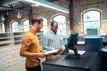 Colleagues working in publishing office smiling while talking