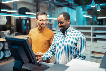 Fototapeta premium Man wearing glasses talking to his dark-skinned colleague