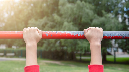 Hanging from the gymnastic bar, hands on bar. Playground, sports and a healthy lifestyle concept