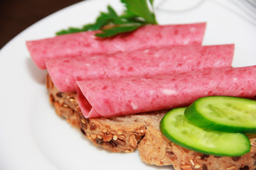 sandwich of rye bread with meat sausage, cucumbers and parsley