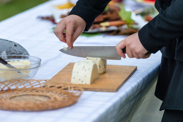 Worker slicing the cheese. Close up of  hands cut with a knife cheese - Image