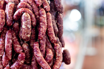 Background with vertically hanged dried sausages in the market pavilion, copy space - image