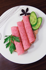 sandwich of rye bread with meat sausage, cucumbers and parsley
