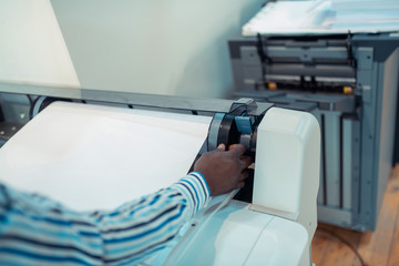 Close up of dark-skinned man using big modern printing technique