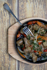 Soup with meat and vegetables. Buryat national dish with onions, carrots and red pepper, fried in a pan on a wooden background