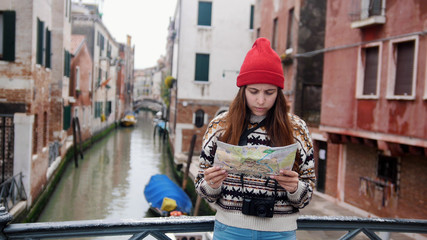 Fototapeta na wymiar A young woman standing above the water channel and looking at the map - Venice, Italy