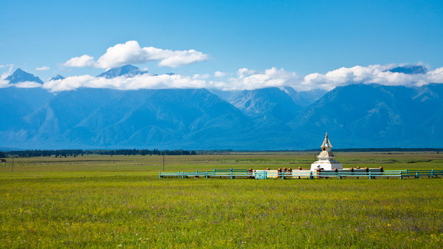 Siberian Tunka valley on the background of Eastern Sayan Mountains in summer sunny day. The Buddhist Stupa in green meadow. Beautiful landscape