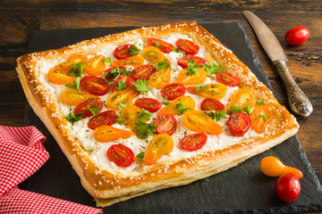 Puff pastry cake with ricotta and cherry tomatoes on wooden rustic table