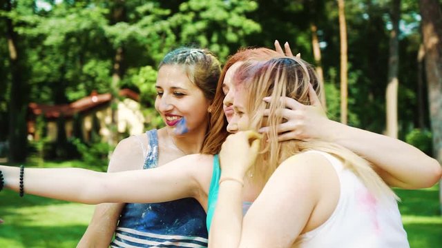 three girls in colorful powder make funny selfie after celebrating Holi festival