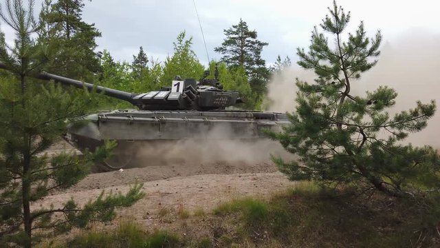 Main battle tank are going to dust on the ground for military exercises. Driving at high speed through the forest
