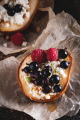 Baked pear with honey, cottage cheese, raspberries and currants. Fresh homemade dessert. Food composition in a low key. Close-up, copy space.