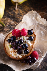 Baked pear with honey, cottage cheese, raspberries and currants. Fresh homemade dessert. Food composition in a low key. Close-up, copy space.