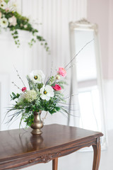 A bouquet of artificial flowers in a vase in the luxurious interior of the room. Soft focus.