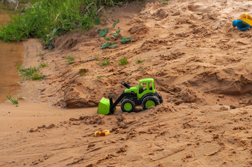Children's toy cars on the sandy beach, in the water on a bright sunny summer day
